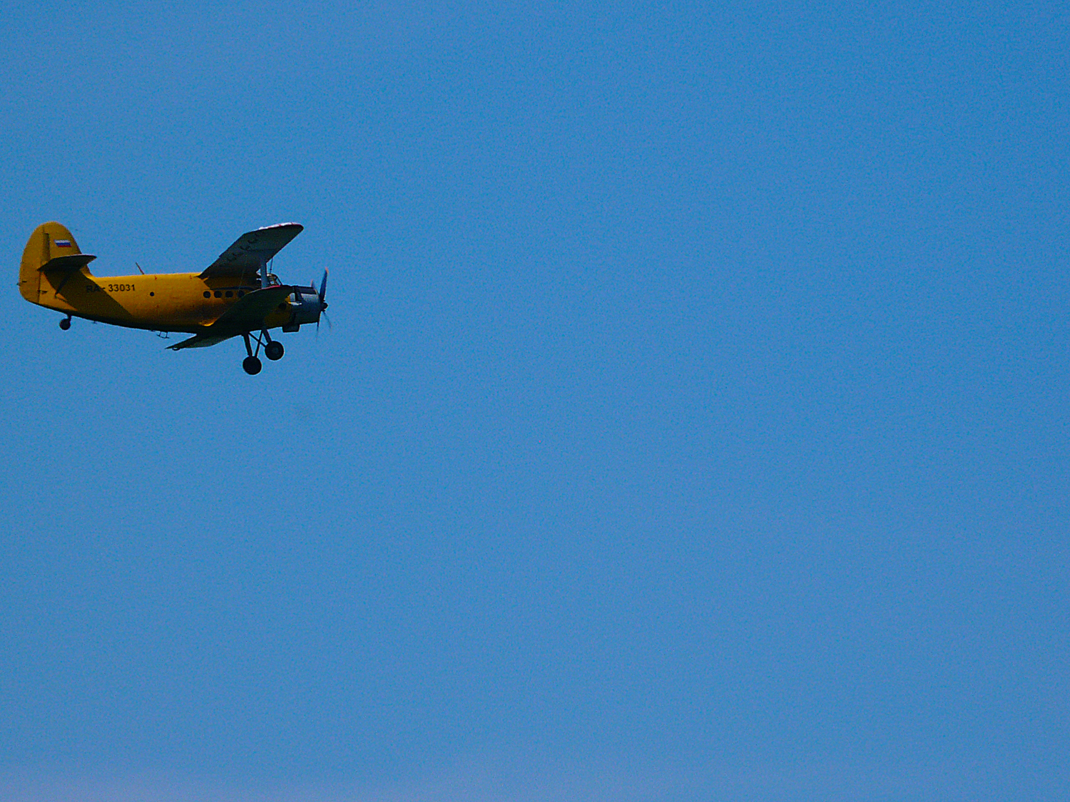 На синем небе жёлтый самолет.