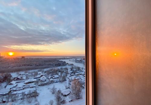 Отражение всходящего солнца в замороженном окне …